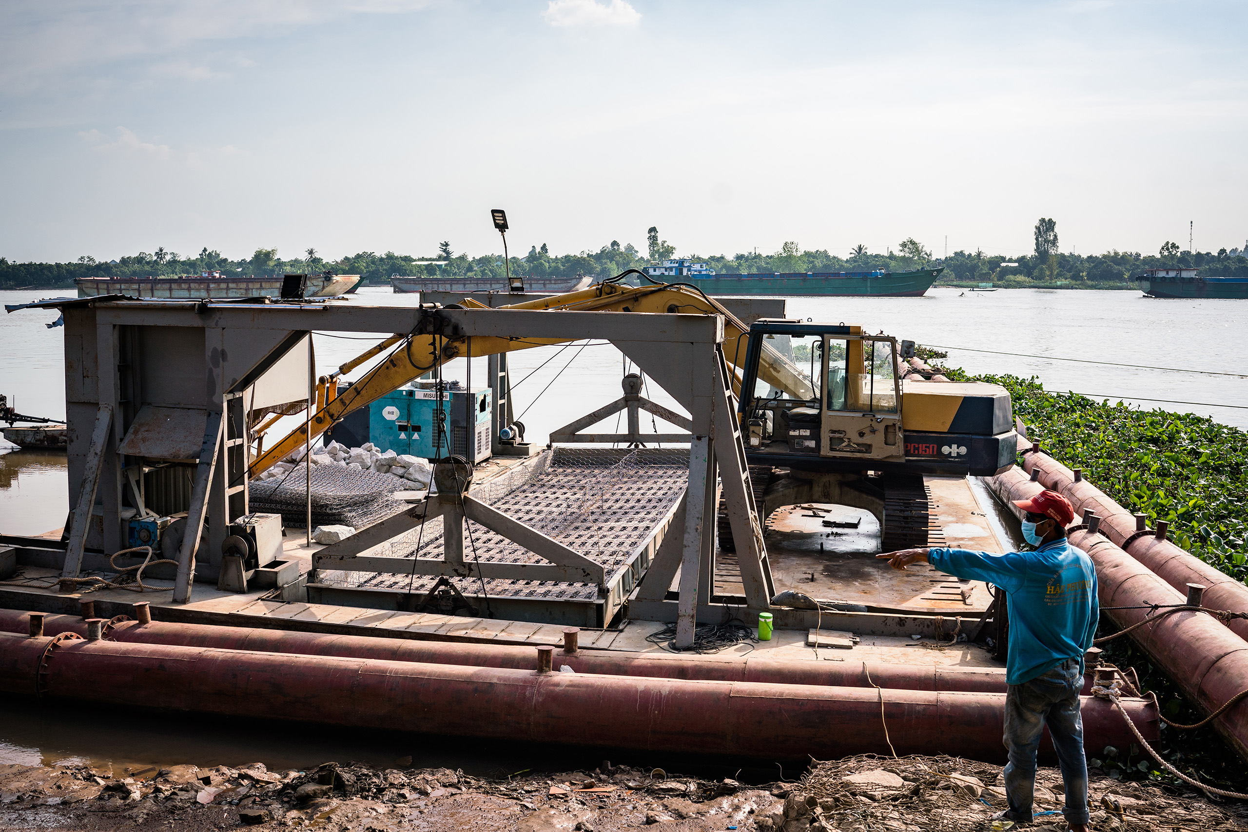 a concrete embankment is being built along the river. This machine is packing rocks to form the embankment’s foundation.
