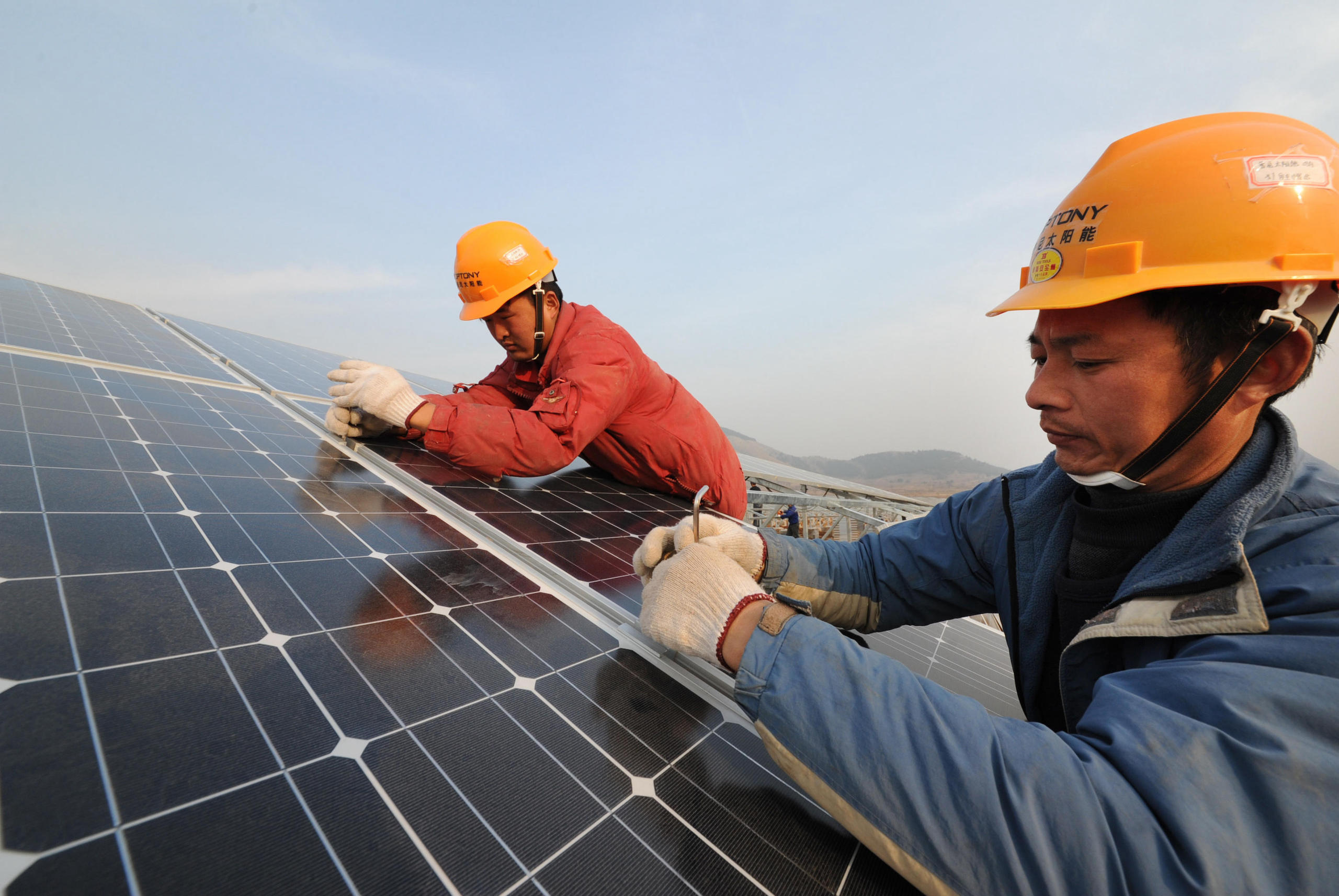 Chinese workers install solar panels at a photovoltaic (PV) power plant in Xiji town, Zaozhuang city