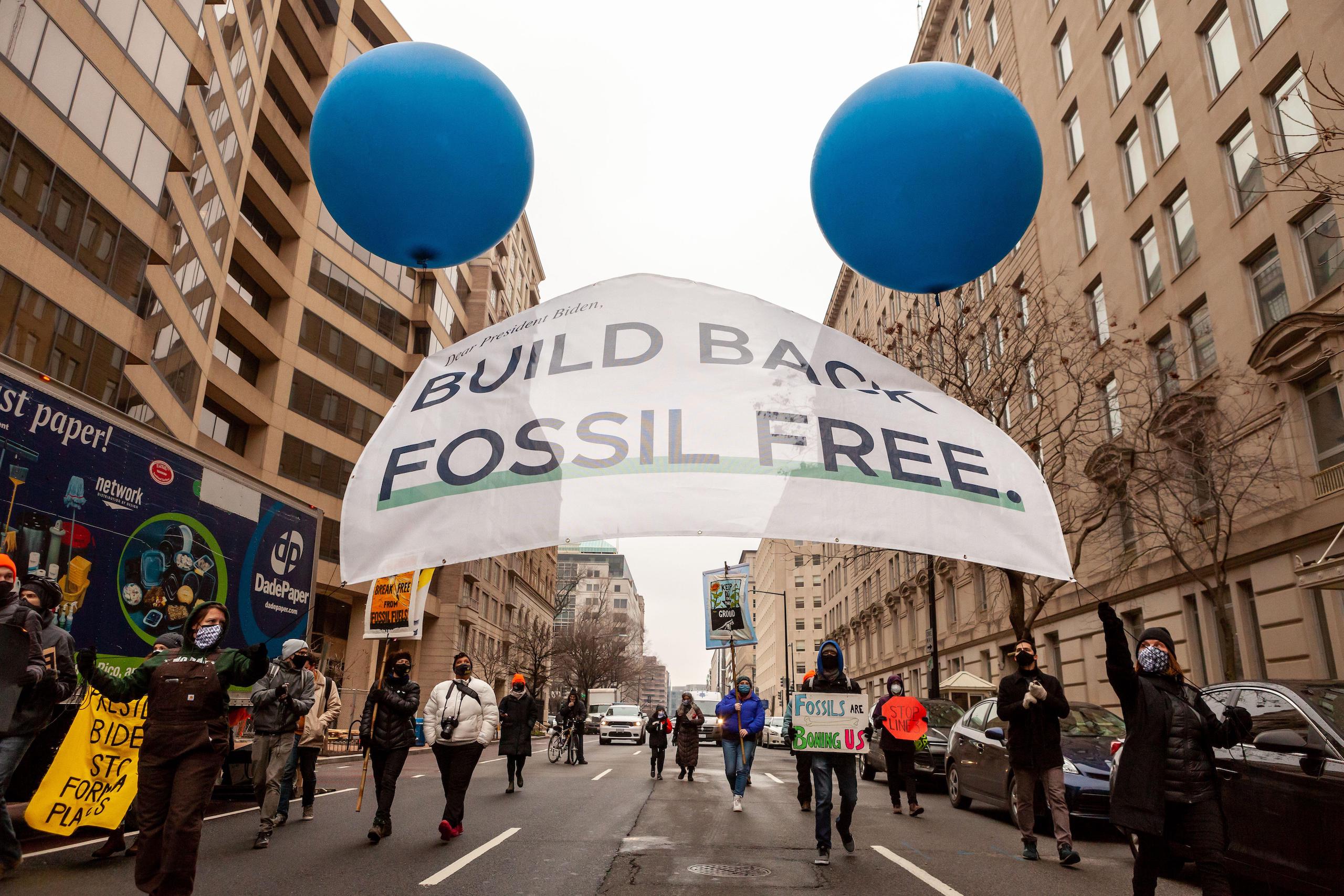 Demonstrators march toward the White House to urge President Biden to phase out fossil fuels
