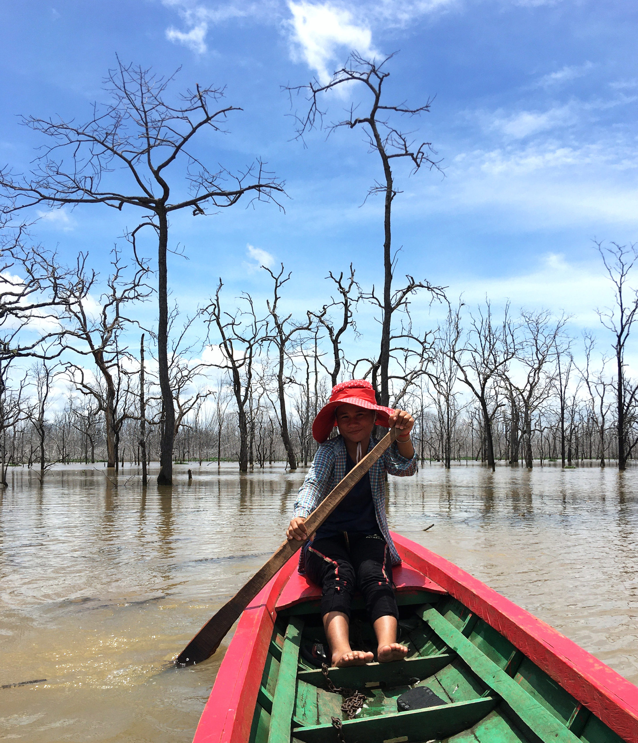 woman paddled boat through area flooded by lower sesan dam, cambodia