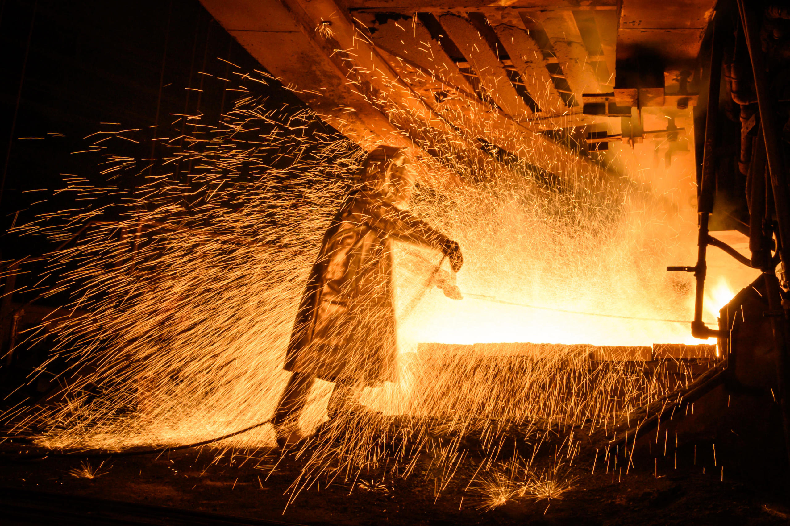 worker in a fire suit seen supervising the flow of hot liquid metal as it flows from a furnace at a nickel plant in Indonesia 