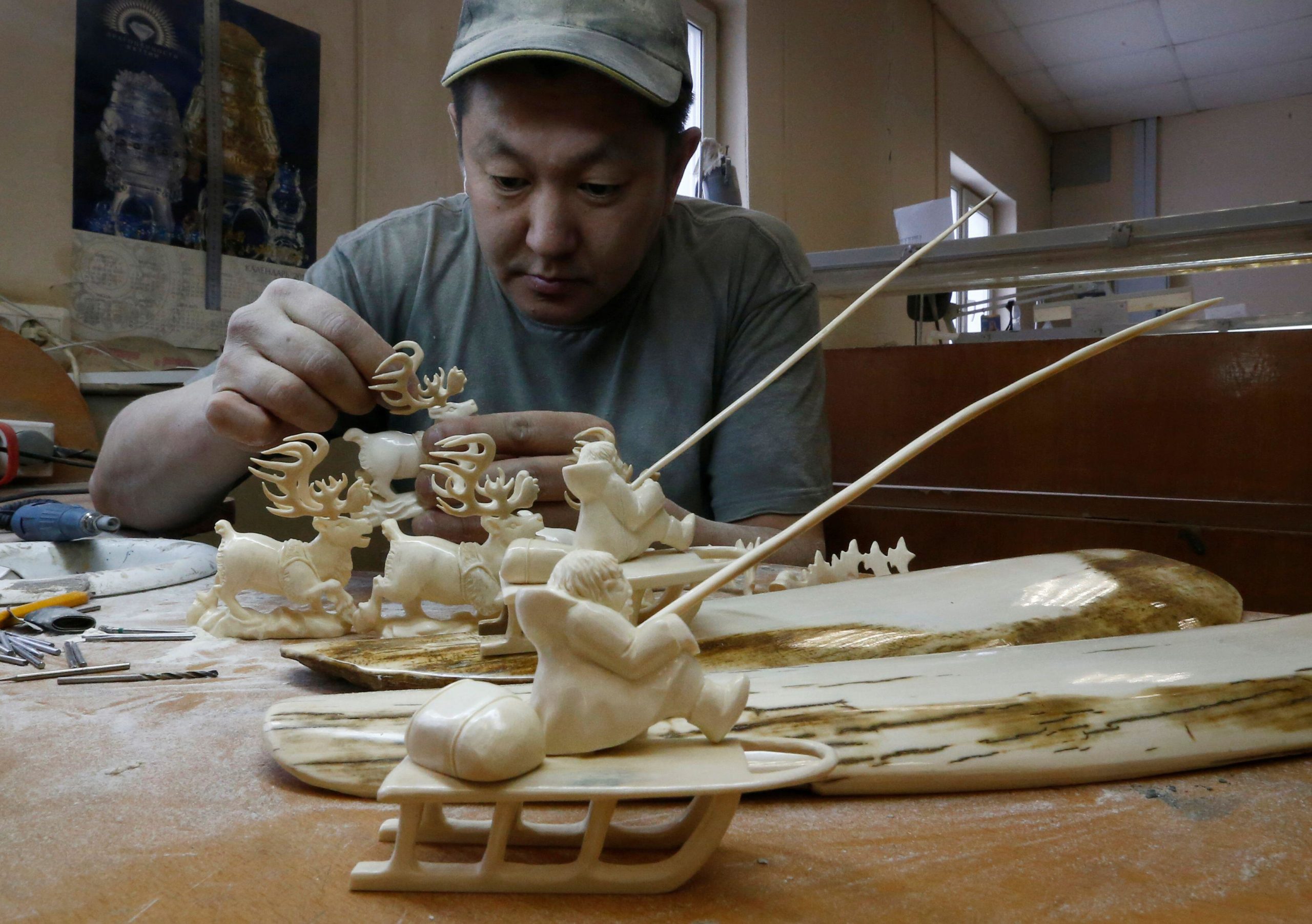 An entrepreneur carves figures from mammoth tusk in Yakutsk. After decades of profit, the mammoth ivory business is in decline in Siberia, mainly due to China’s 2018 ban on elephant ivory. (Image: Sergei Karpukhin / Alamy)