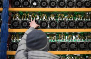 A worker checks the fan on a miner, at the cryptocurrency farming operation