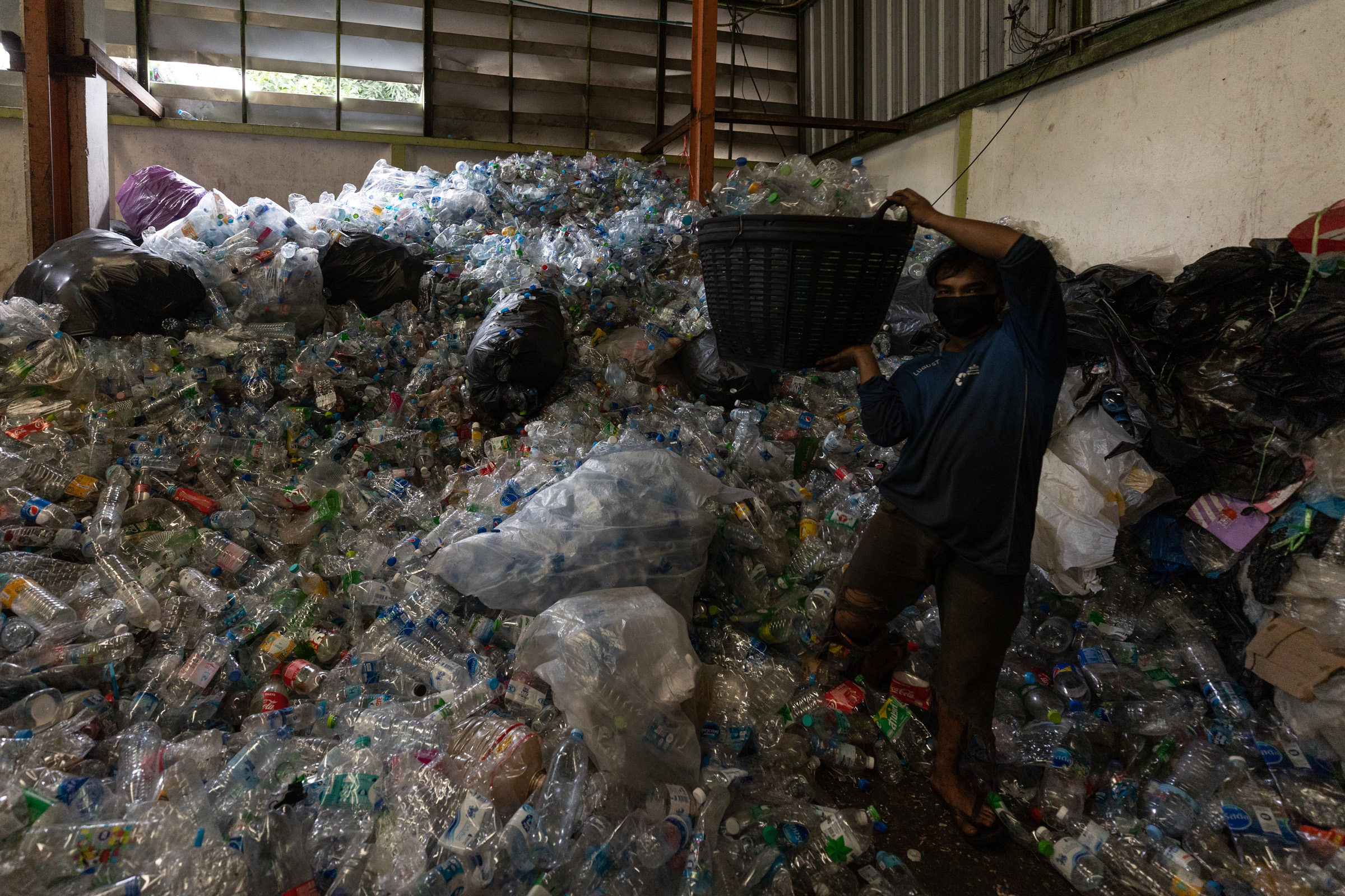 A workers adds plastic bottles to a compressing machine inside a recycling company in Bangkok.