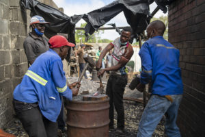 At a backyard workshop in Zimbabwe’s Bulawayo, workers melt scrap metal with coke and use traditional smithing techniques to fashion small steel items. Steel supply in the country has been strained following the demise of large-scale production, leading to a rush for scrap metals and a growth in small companies that process it. (Image: <a href="https://www.kbmpofu.com/">KB Mpofu</a> / China Dialogue)