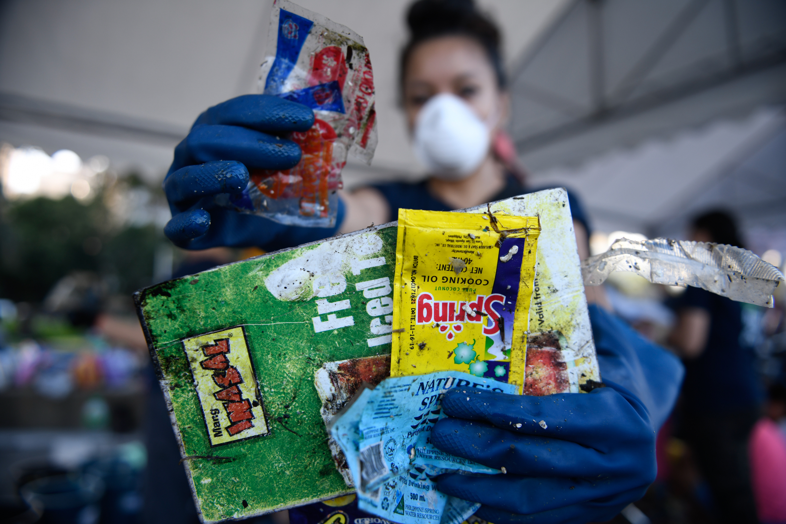 Woman holds up pieces of rubbish collected at the Manila Bay clean-up and plastic waste brand audit in Roxas Blvd, Metro Manila.
