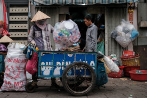 An informal waste worker piles recyclable plastic bottles onto her cart in southern Vietnam’s Ho Chi Minh City