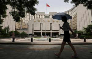 A woman walks past the headquarters of the People's Bank of China (PBOC),