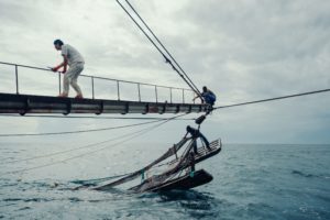 A Chinese fishing vessel in the waters of Guinea-Bissau. The captain (left) and two local sailors (right) are trying to release a trapped net.