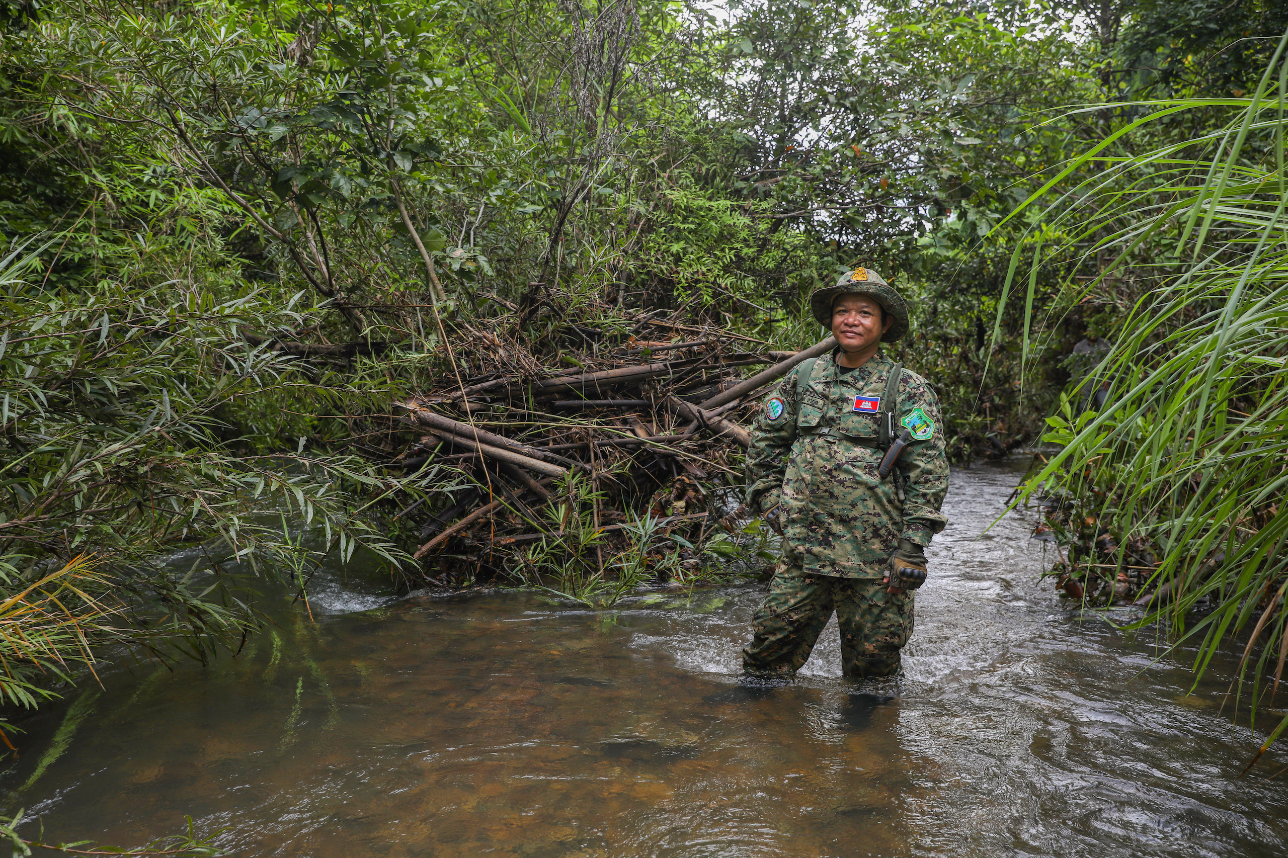 Kam Phon, chief of the Voen Sai Ranger Station in Virachey National Park stands in a river with dense forest behind