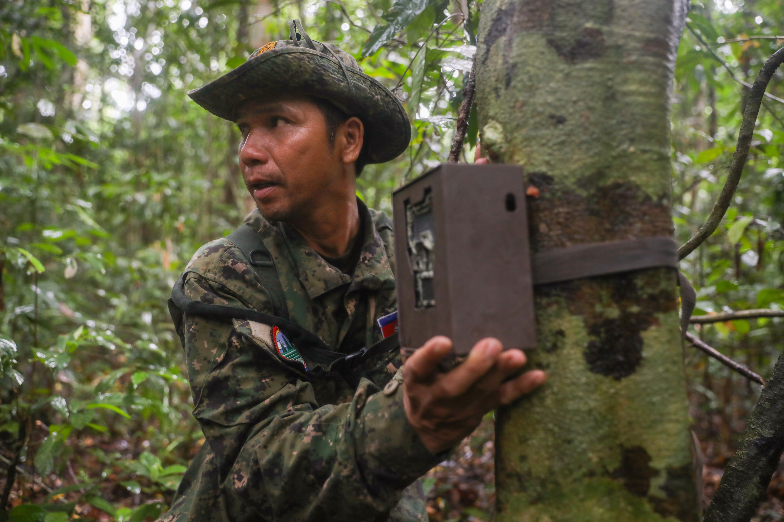 a forest ranger working for the Ministry of Environment, adjusts the angle of a camera trap in Virachey National Park as part of a biodiversity study