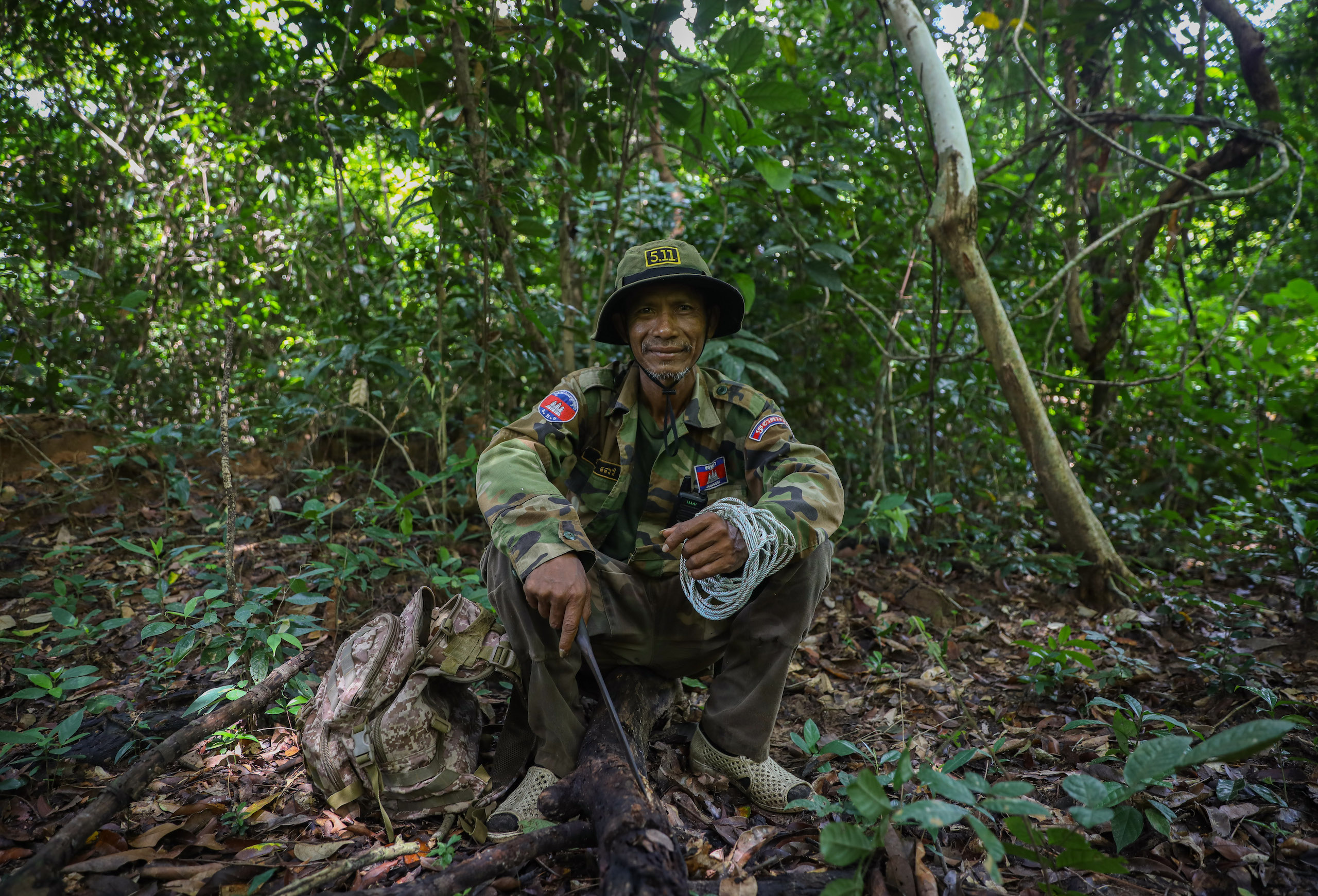 A community ranger in Phnom Tnout-Phnom Pok Wildlife Sanctuary sits on the ground looking at the camera, holding rope