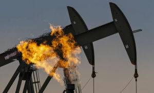 A natural gas flare - a major source of methane emissions - beside pumpjacks pumping crude oil at a facility in North Dakota, US