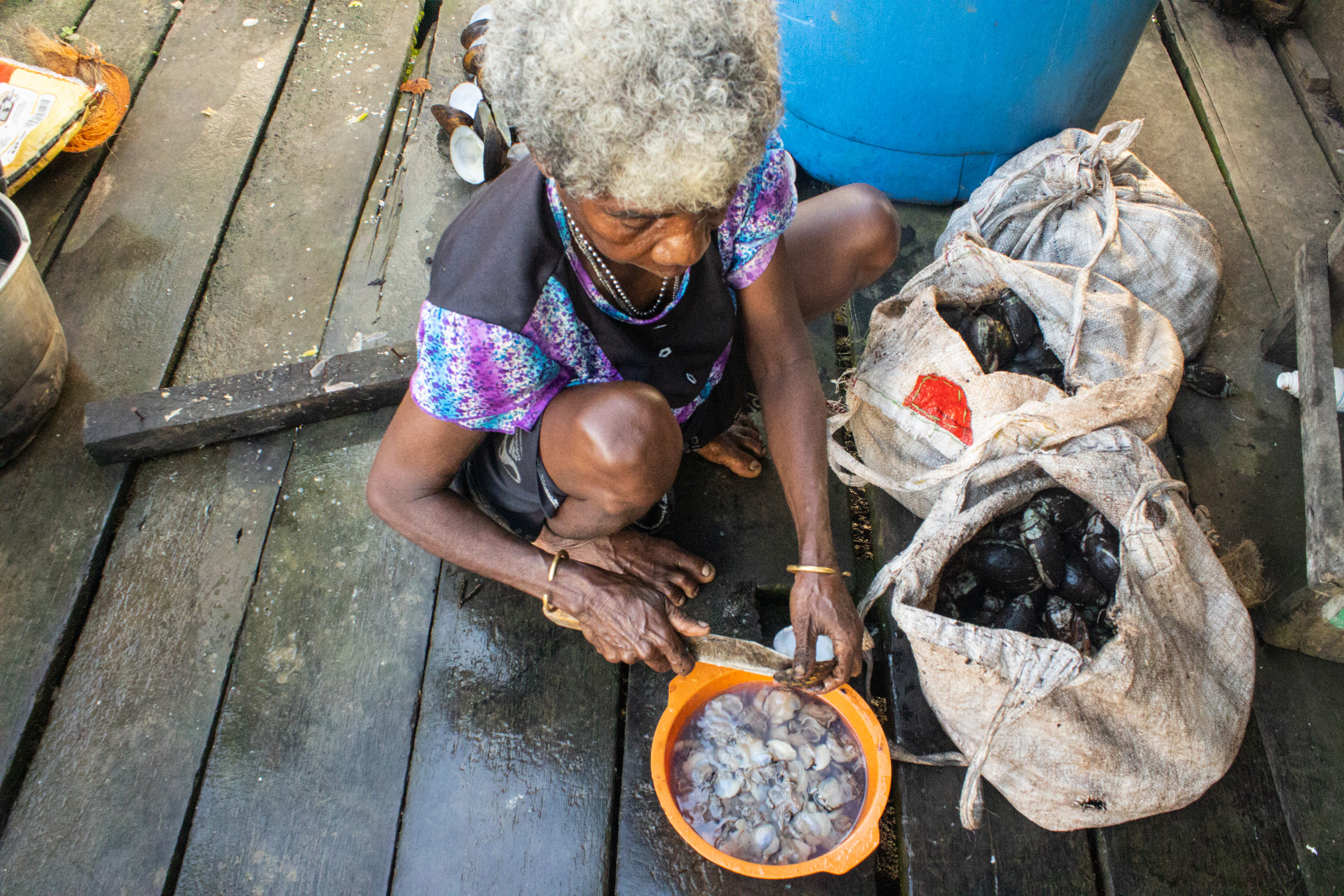 Maria Sawat cleans and prepares clams collected from the river