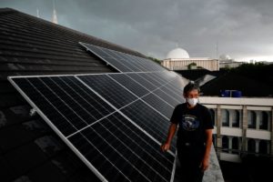 a 56-year-old technician wearing a face mask walks on the roof of the Jakarta Cathedral that is installed with solar panels. Indonesia