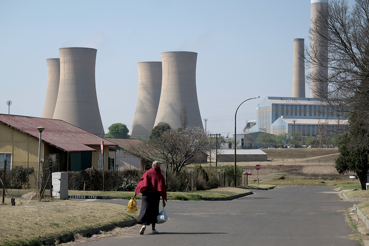 person walking on road with cooling towers in the distance