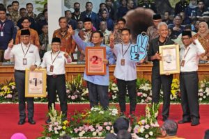 Six men pose for photographs on a red carpet