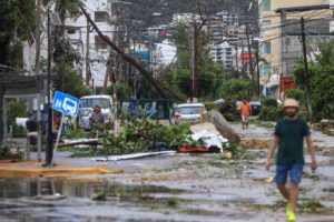 Hurricane destruction; a street littered with fallen trees, broken signs and other debris