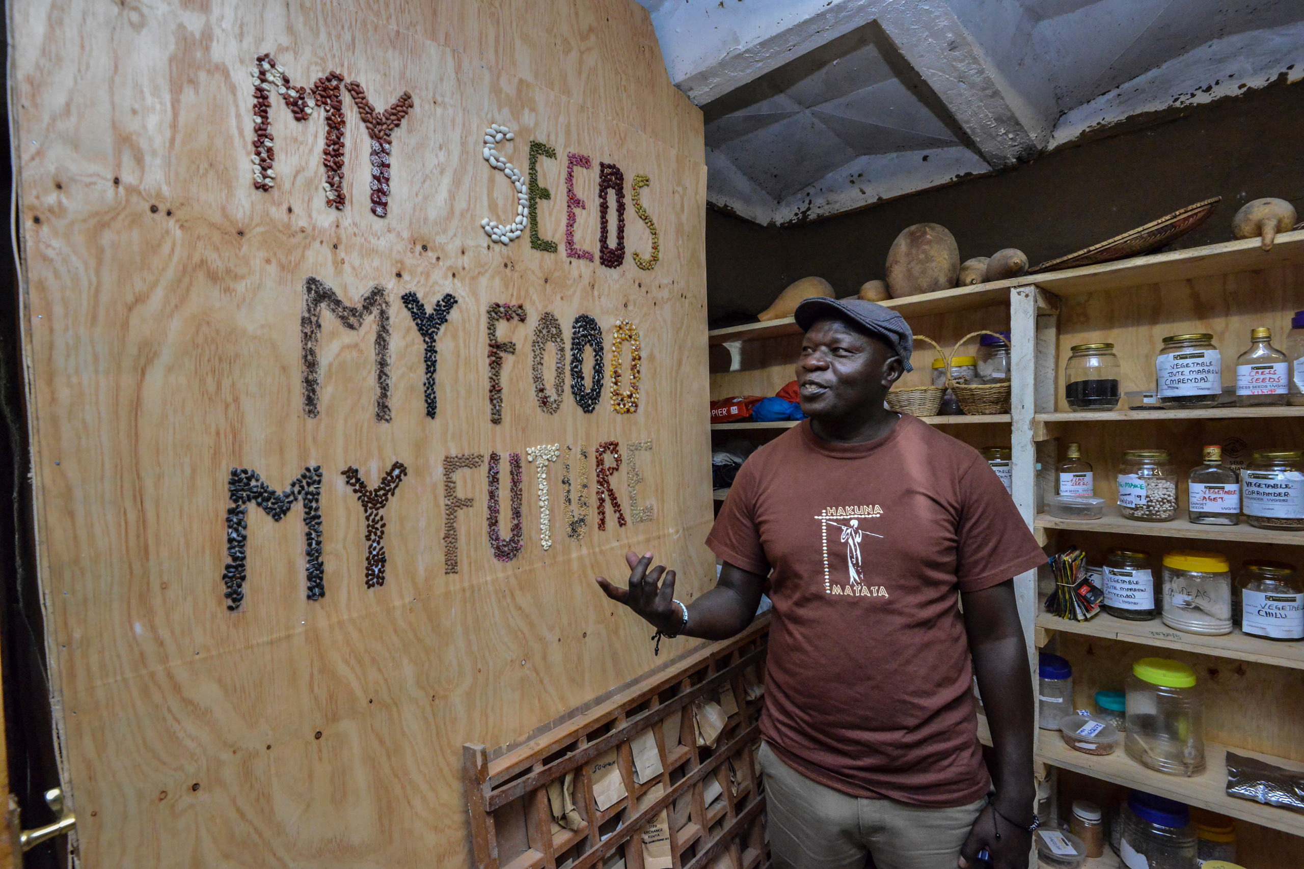 Uśmiechnięty mężczyzna wskazujący na ścianę z napisem „moje nasiona, moje jedzenie, moja przyszłość”
