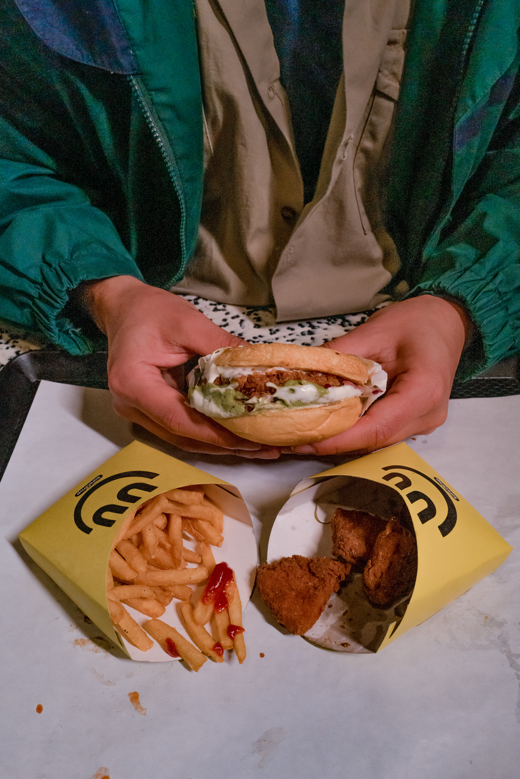 Alguien sosteniendo una hamburguesa con papas fritas sobre la mesa