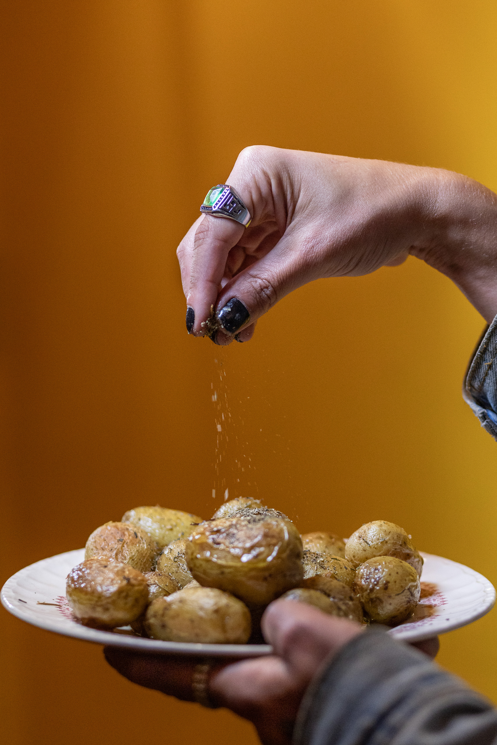 Una mano espolvorea sal sobre un plato de patatas