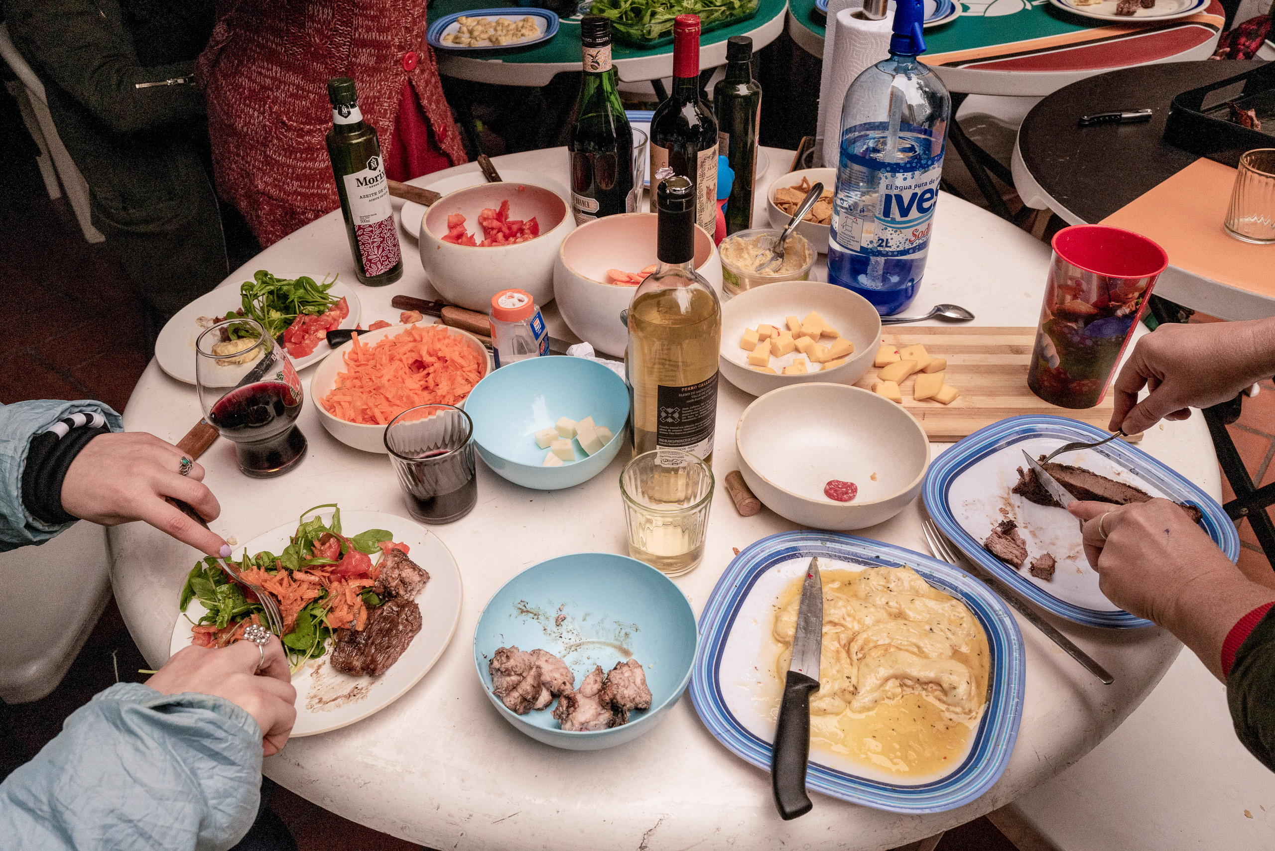 Una mesa con comida y botellas de vino.