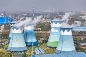a group of coal power stations with buildings in the background